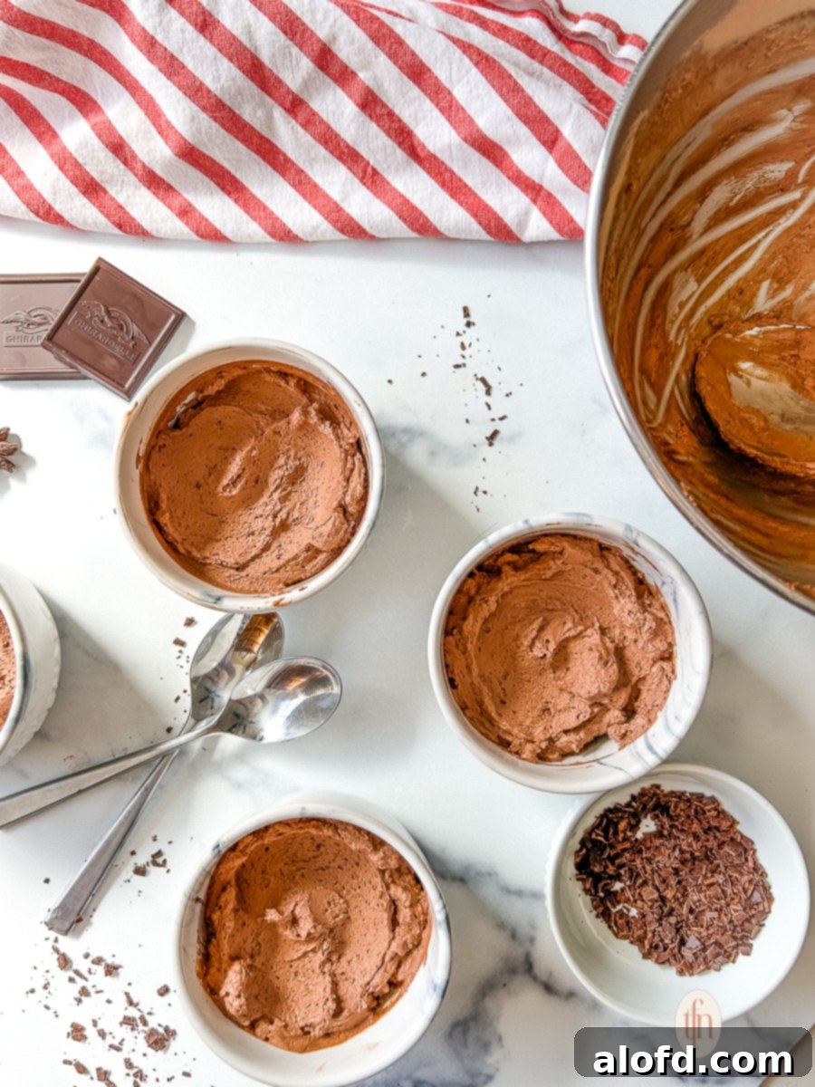 Simple Decadent Chocolate Mousse 12 Three small white bowls of mousse without topping on a white surface.