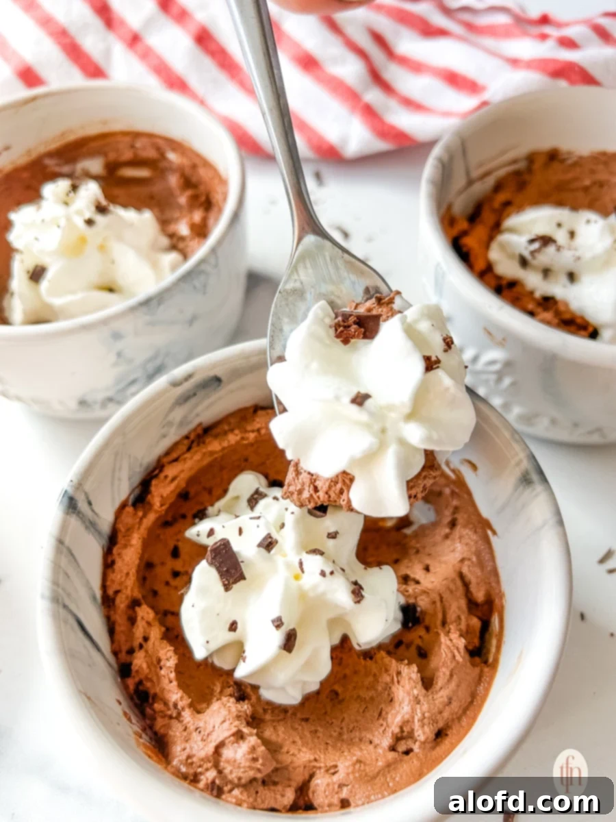 Simple Decadent Chocolate Mousse 13 Spoon lifting whipped cream and mousse from a small bowl.