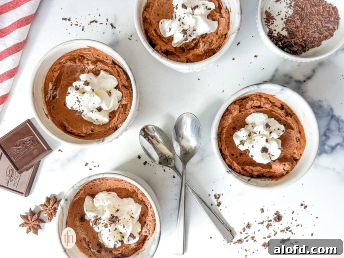 Simple Decadent Chocolate Mousse 14 Four small bowls filled with chocolate mousse on a white surface.