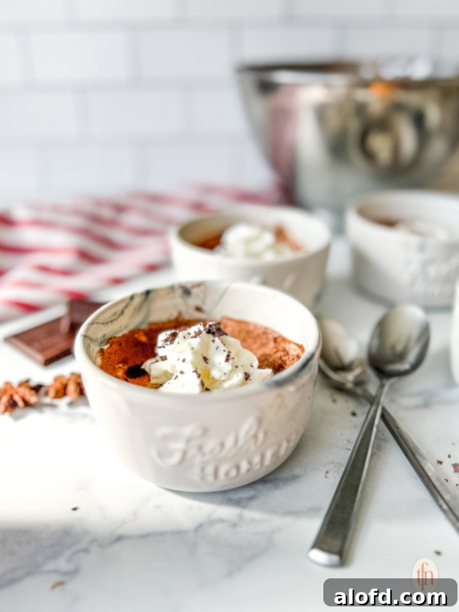 Simple Decadent Chocolate Mousse 6 Individual cups filled with chocolate mousse and topped with whipped cream and shaved chocolate on a white background.