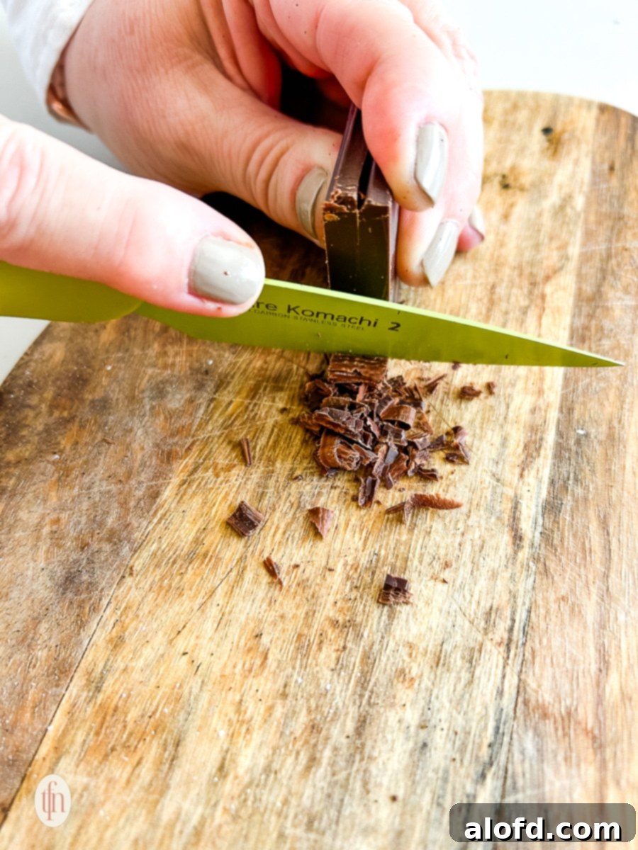 Simple Decadent Chocolate Mousse 10 Shaving chocolate with a knife on a cutting board.
