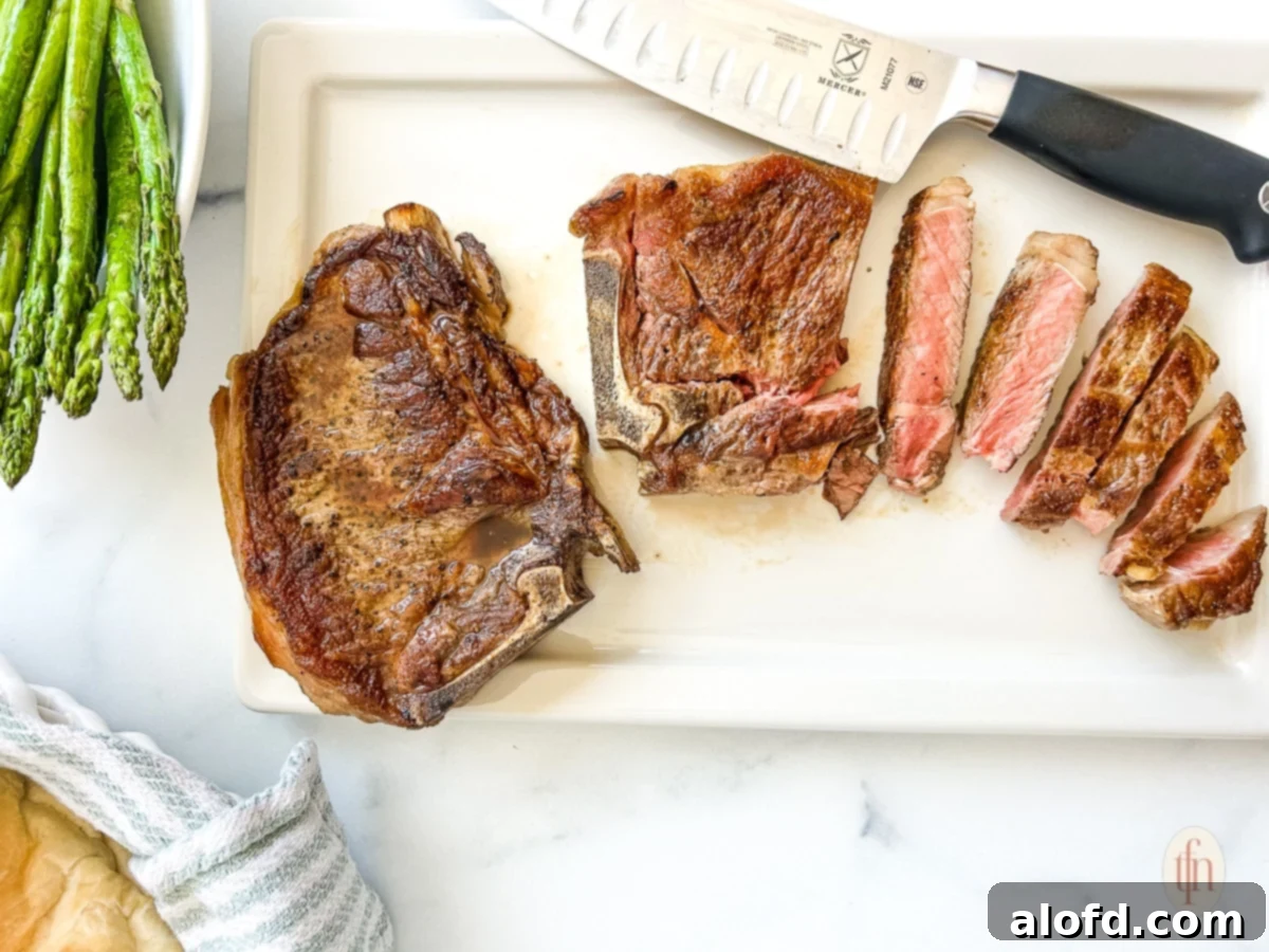 Two juicy, bone-in NY strip steaks on a cutting board. One of the steaks is partially sliced, revealing its succulent medium-rare interior.