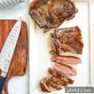 Grilled strip steak cooked to medium rare, partially cut in slices on a cutting board, ready to serve.