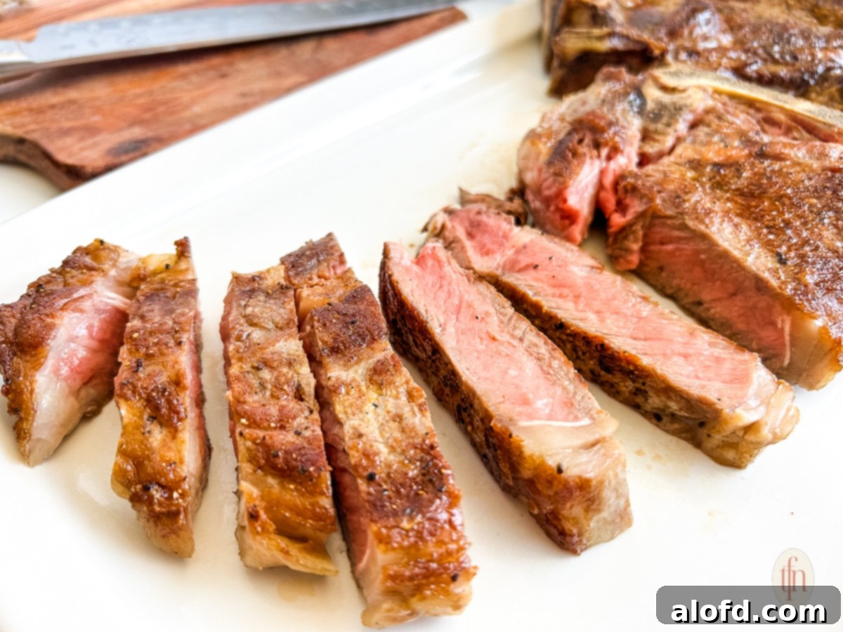 Close-up of perfectly sliced shell steak on a platter, revealing its medium-rare doneness and juicy texture, ready for serving.