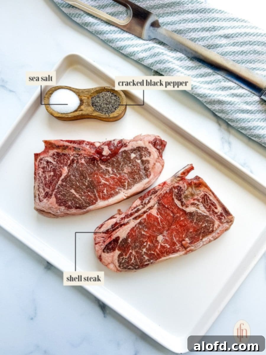 Ingredients for shell steak recipe, including two raw bone-in NY strip steaks, coarse sea salt, and whole black peppercorns.