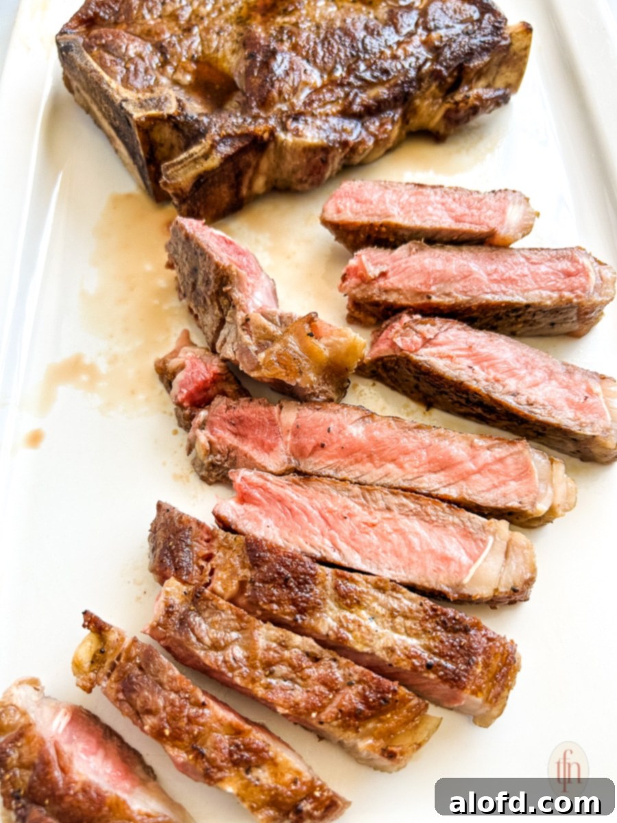 Close-up of perfectly sliced grilled strip steak arranged on a white platter, demonstrating the optimal 'against the grain' cutting technique.