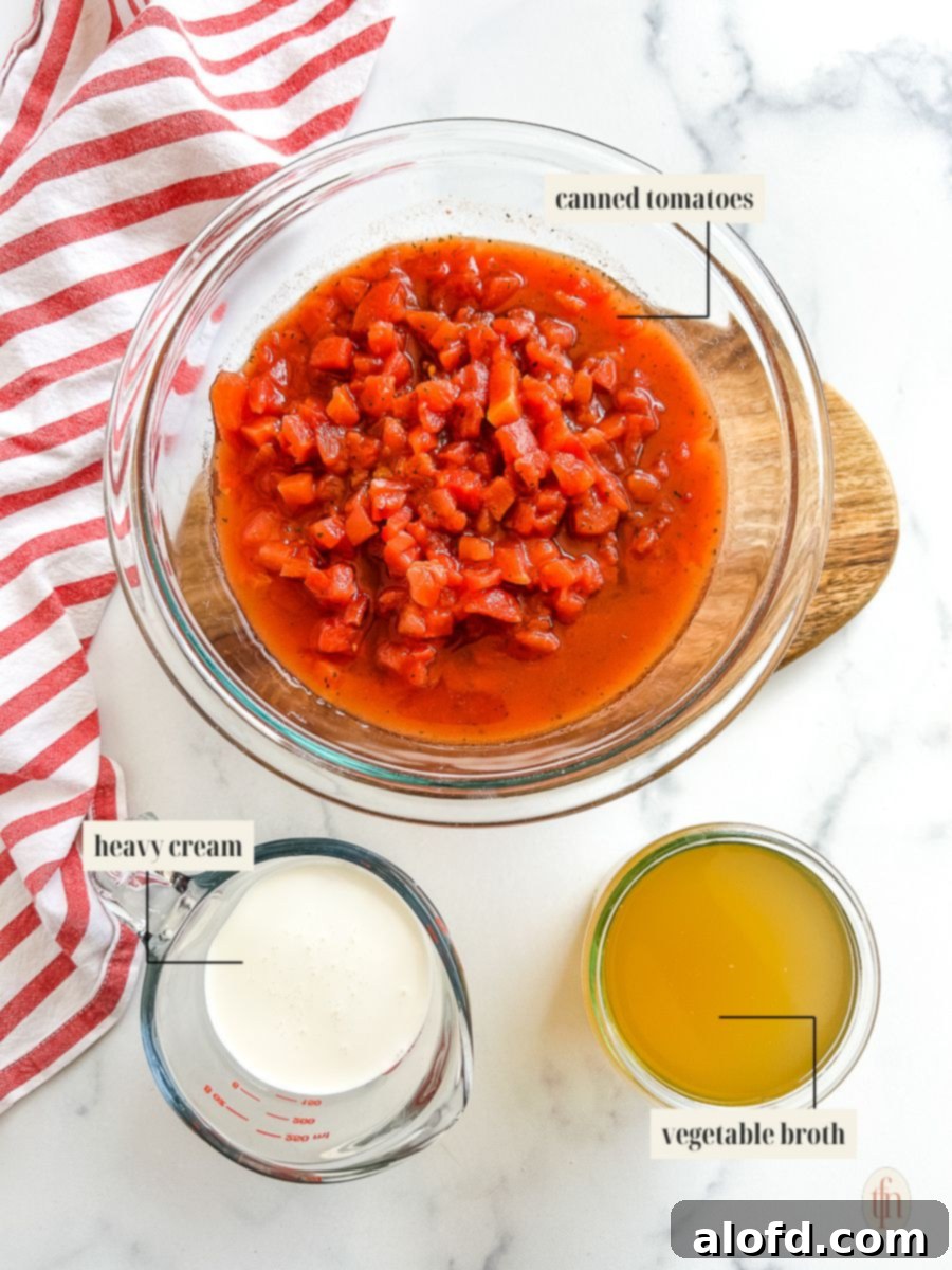 The Ultimate 3-Ingredient Tomato Soup 4 Labeled ingredient image showcasing canned tomatoes, vegetable broth, and heavy cream for a 3-ingredient tomato soup recipe.