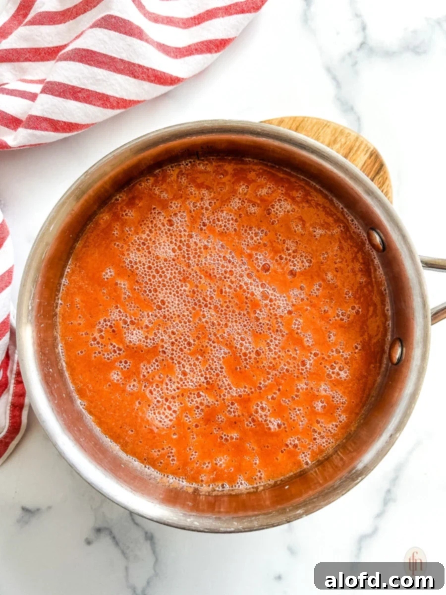 The Ultimate 3-Ingredient Tomato Soup 6 A pot of simmering tomato soup on a stovetop, showing the gentle bubbling for flavor development.