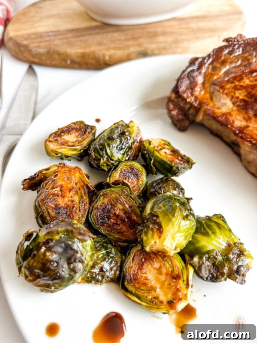 Roasted brussel sprouts on a white plate, glistening with maple balsamic glaze.