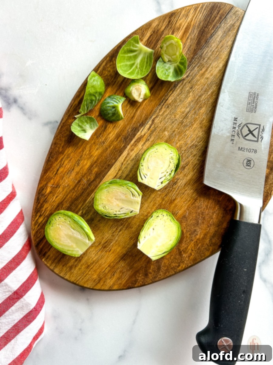 Cutting brussel sprouts on a cutting board with a chef's knife, demonstrating proper preparation.
