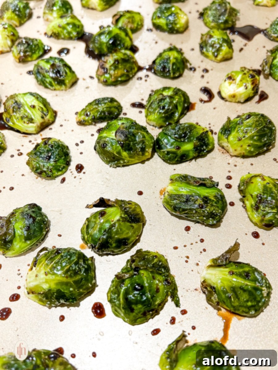 Sprouts brushed with balsamic glaze on a baking sheet, ready for final roast.