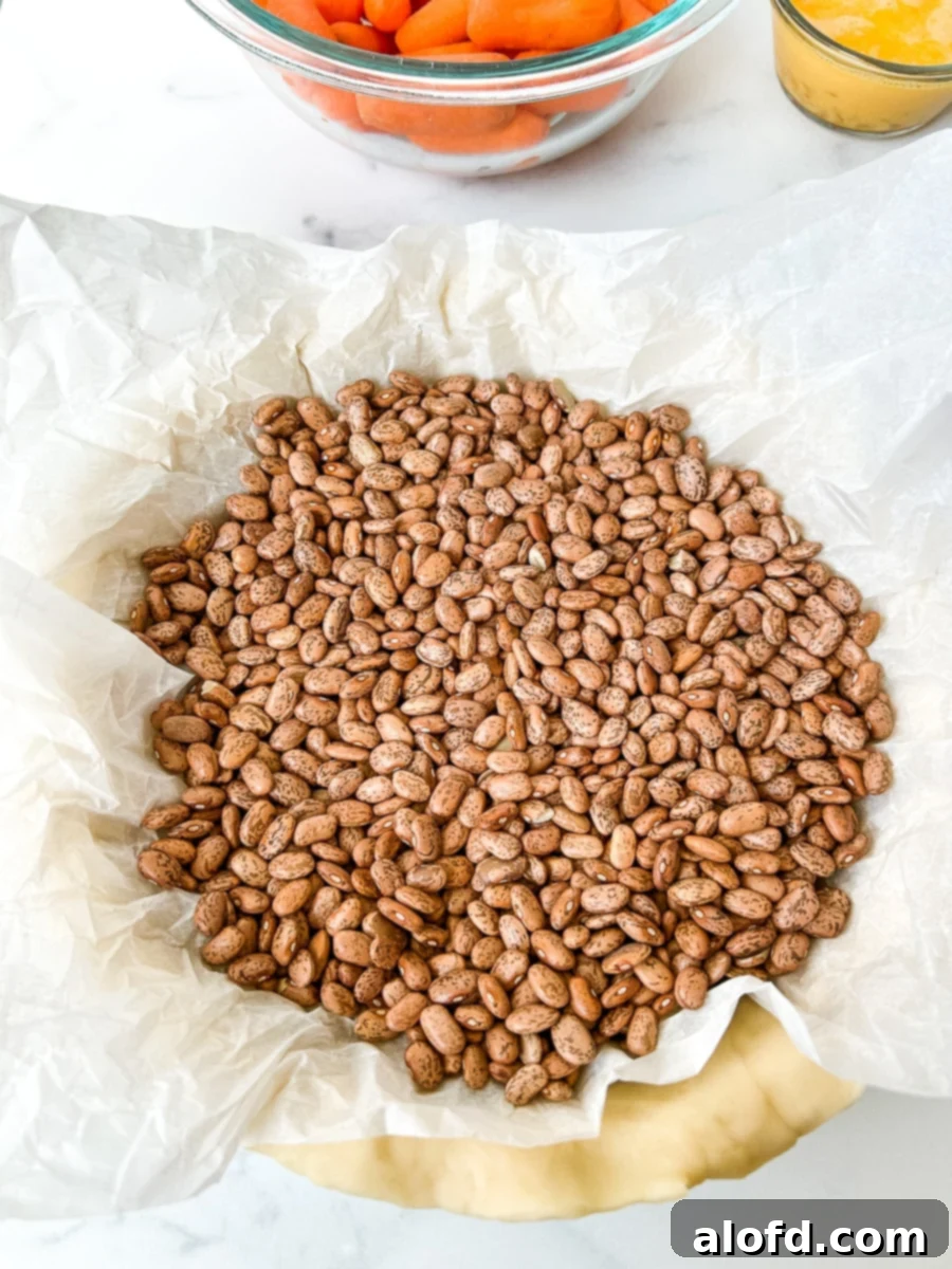 An unbaked pie crust topped with parchment paper and dried beans.