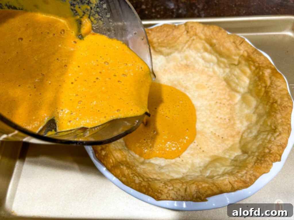 Pouring carrot pie filling into a baked pie crust.