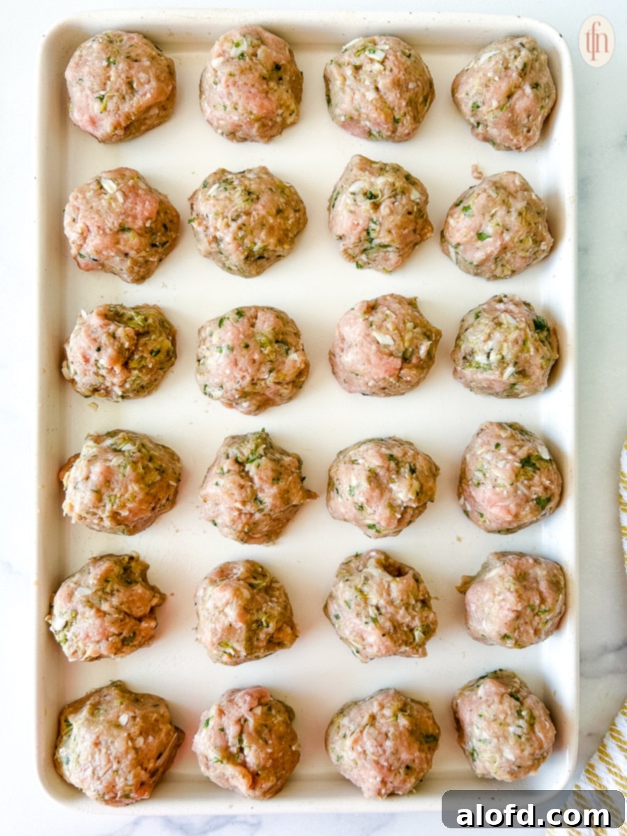 Turkey zucchini meatballs evenly spaced on a baking tray, ready for the oven.