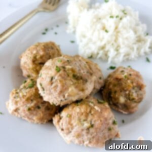 Turkey zucchini meatballs on a white plate next to a fork, showcasing a square view of the dish.