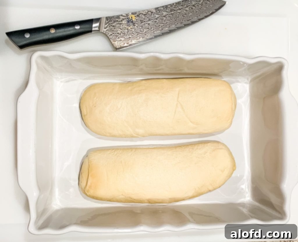 Effortless Overnight French Toast Bake 6 Two loaves of Bridgford Ready-Dough, slightly thawed and ready for preparation, sitting on a wooden cutting board.