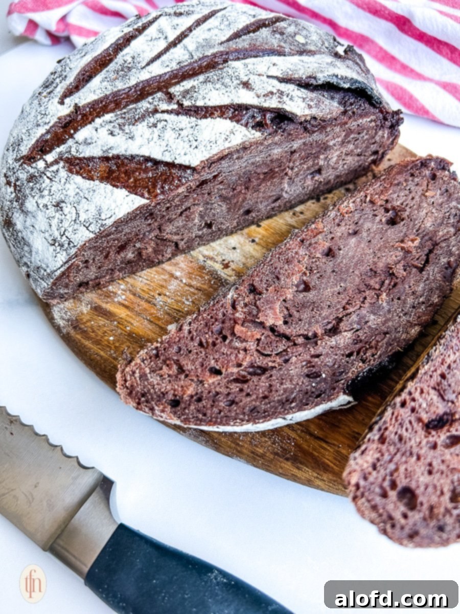 Decadent Chocolate Sourdough 3 A perfectly sliced loaf of chocolate sourdough bread on a wooden cutting board, showcasing its rich brown color and abundant chocolate chips within the crumb.