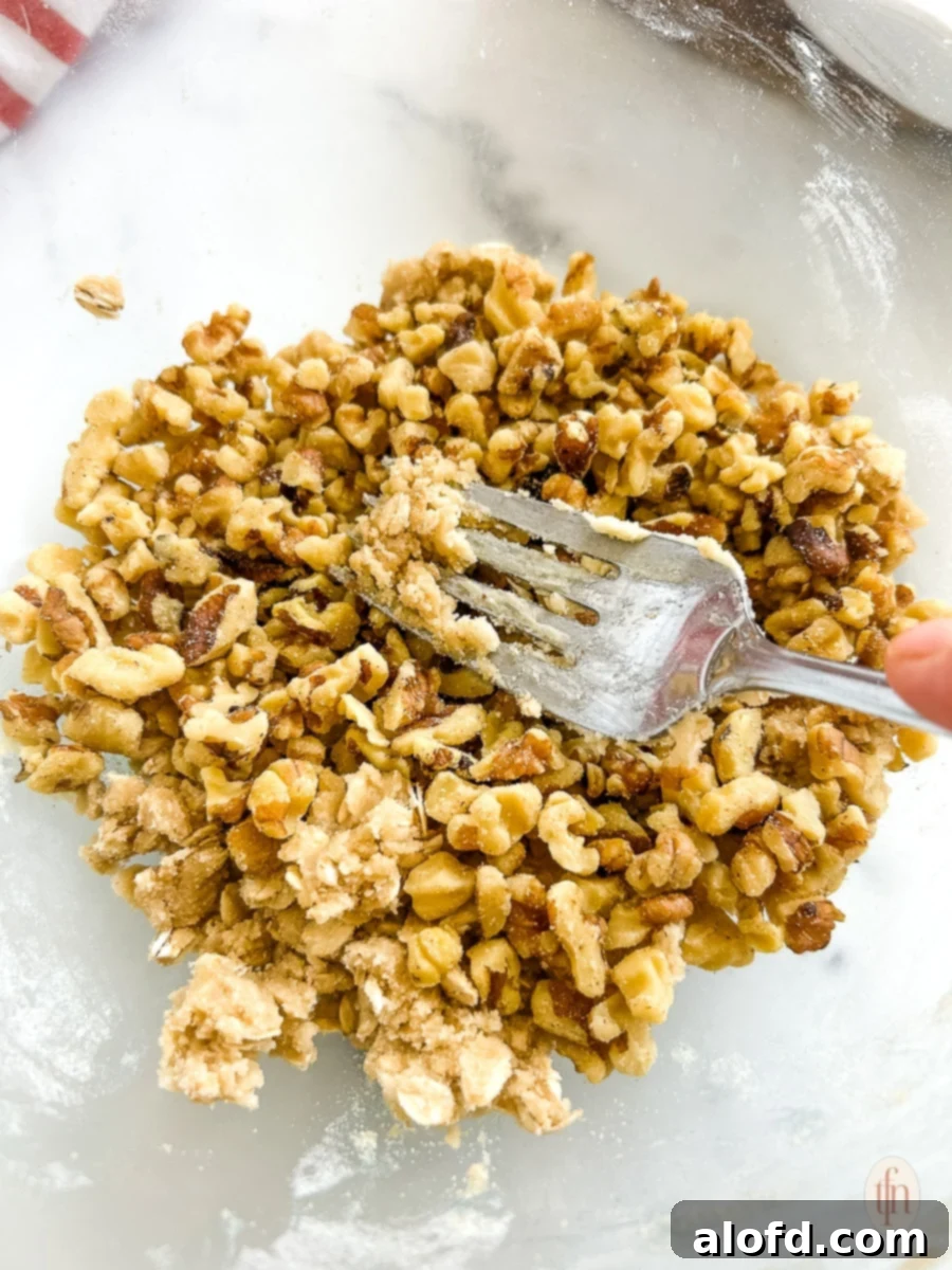 Golden Carrot Bake 7 Mixing the crumb topping ingredients with a fork in a glass bowl, aiming for a coarse, sandy texture for the sweet carrot casserole.
