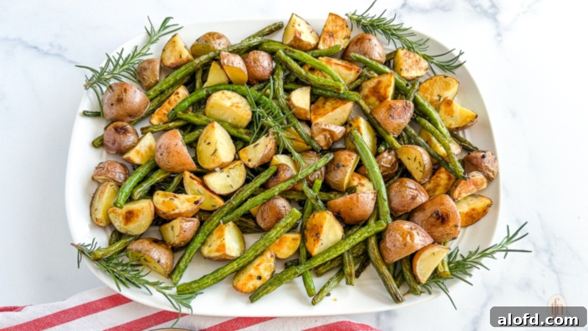 Garlic Herb Roasted Green Beans and Potatoes 10 A large platter generously filled with perfectly roasted green beans and potatoes, arranged horizontally on a white background, highlighting their rich color and texture.