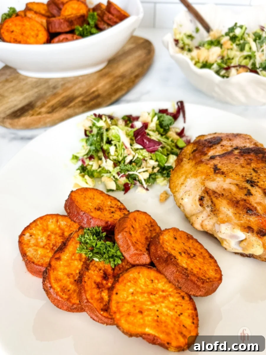 A white plate featuring baked sweet potato slices alongside roasted meat and another green side dish.