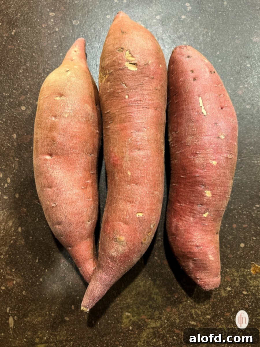 Three large sweet potatoes displayed on a kitchen counter.