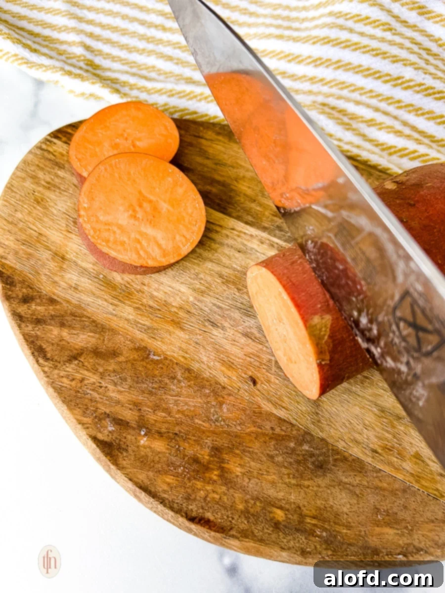 Slicing sweet potatoes with a knife on a wooden cutting board.