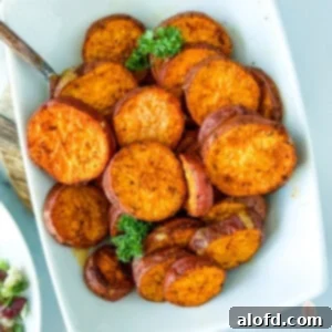 Roasted sweet potato slices in a white serving bowl, garnished with fresh herbs.