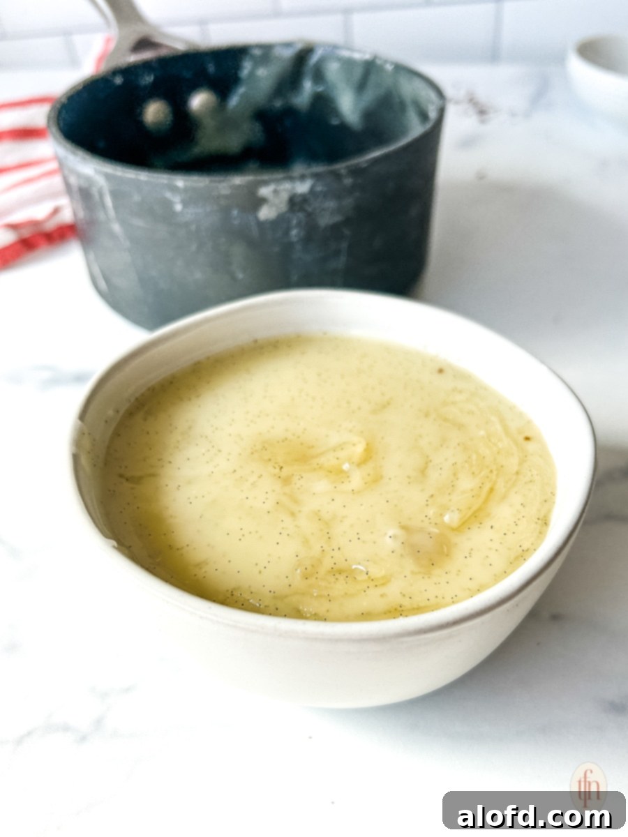 Velvety Vanilla Sauce for Bread Pudding 9 Vanilla sauce poured into a white bowl on a white background.