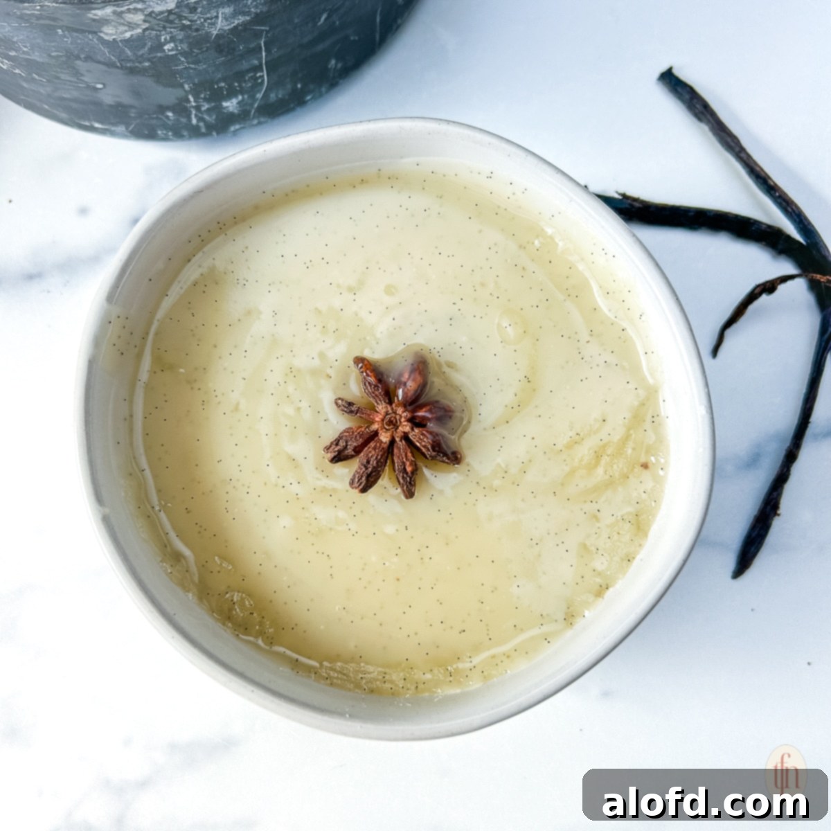 Velvety Vanilla Sauce for Bread Pudding 10 Creamy vanilla sauce garnished with star anise, in a small white bowl.