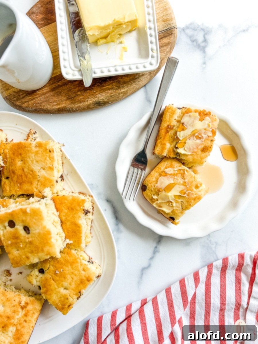 Effortless Sheet Pan Pancakes from Mix 3 A slice of sheet pan pancake served on a white plate with syrup drizzled over the top and a fork ready to enjoy.