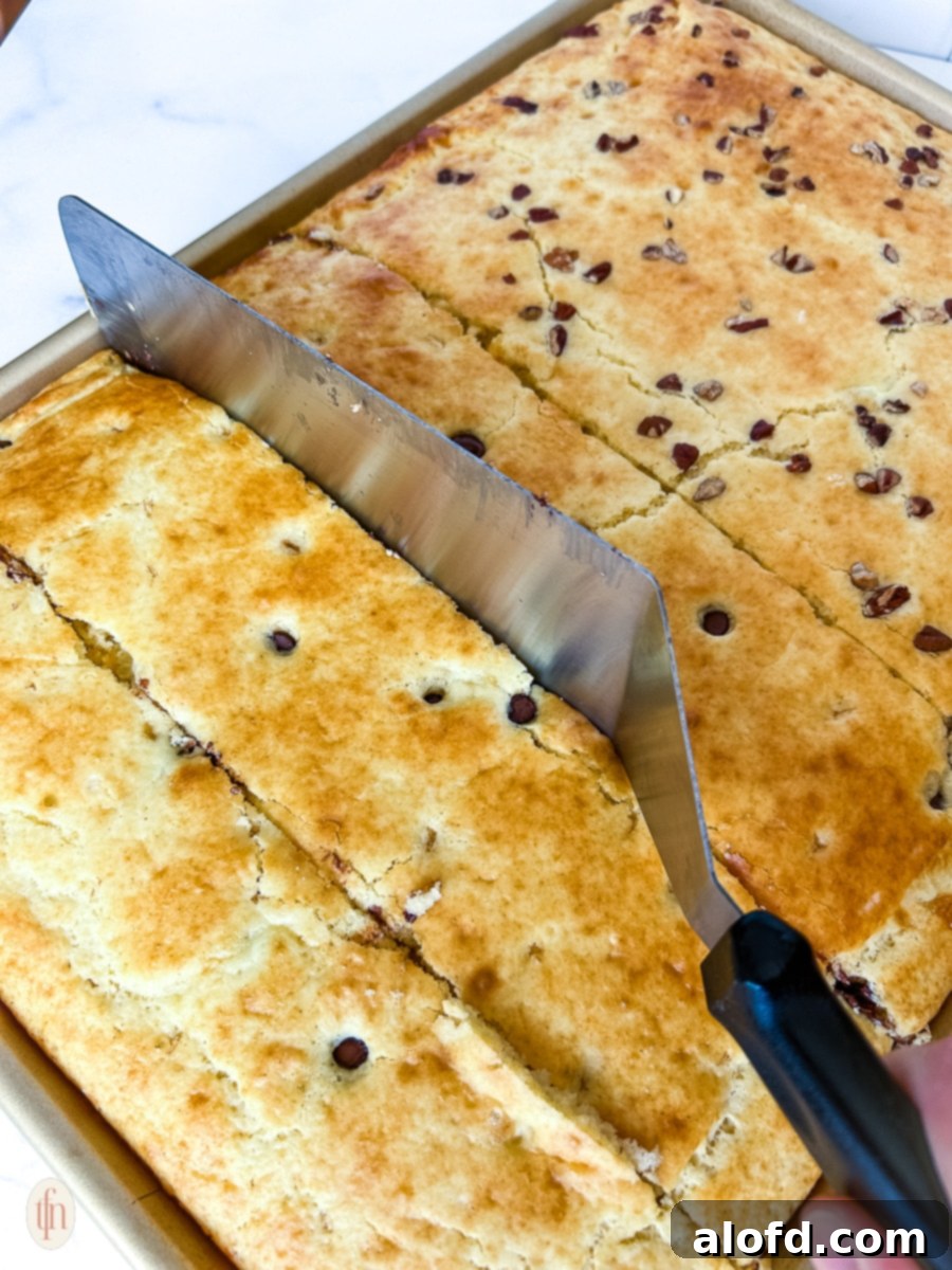 Effortless Sheet Pan Pancakes from Mix 8 Sheet pan pancakes being cut into squares with a metal spatula directly in the pan.