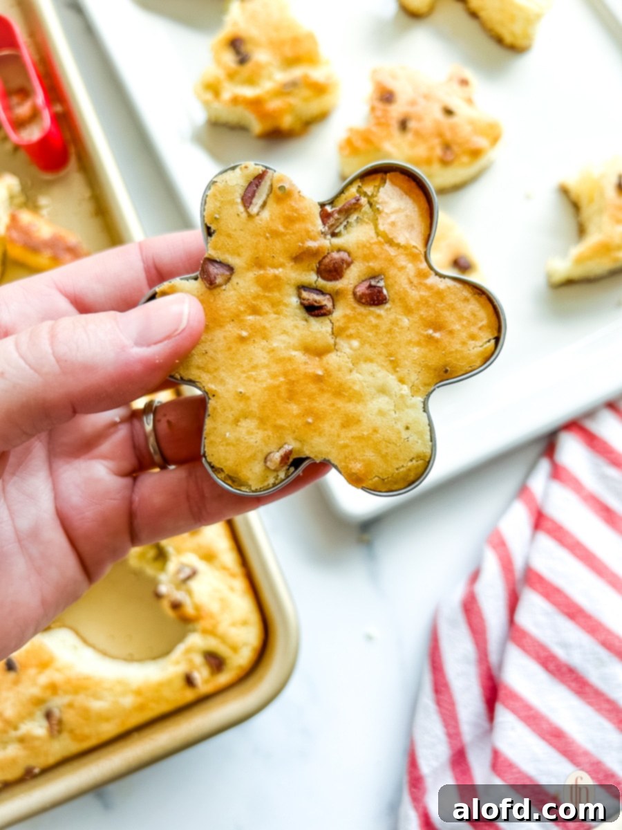 Effortless Sheet Pan Pancakes from Mix 9 Baked sheet pan pancakes being cut into festive shapes using a cookie cutter, ready for a special occasion.