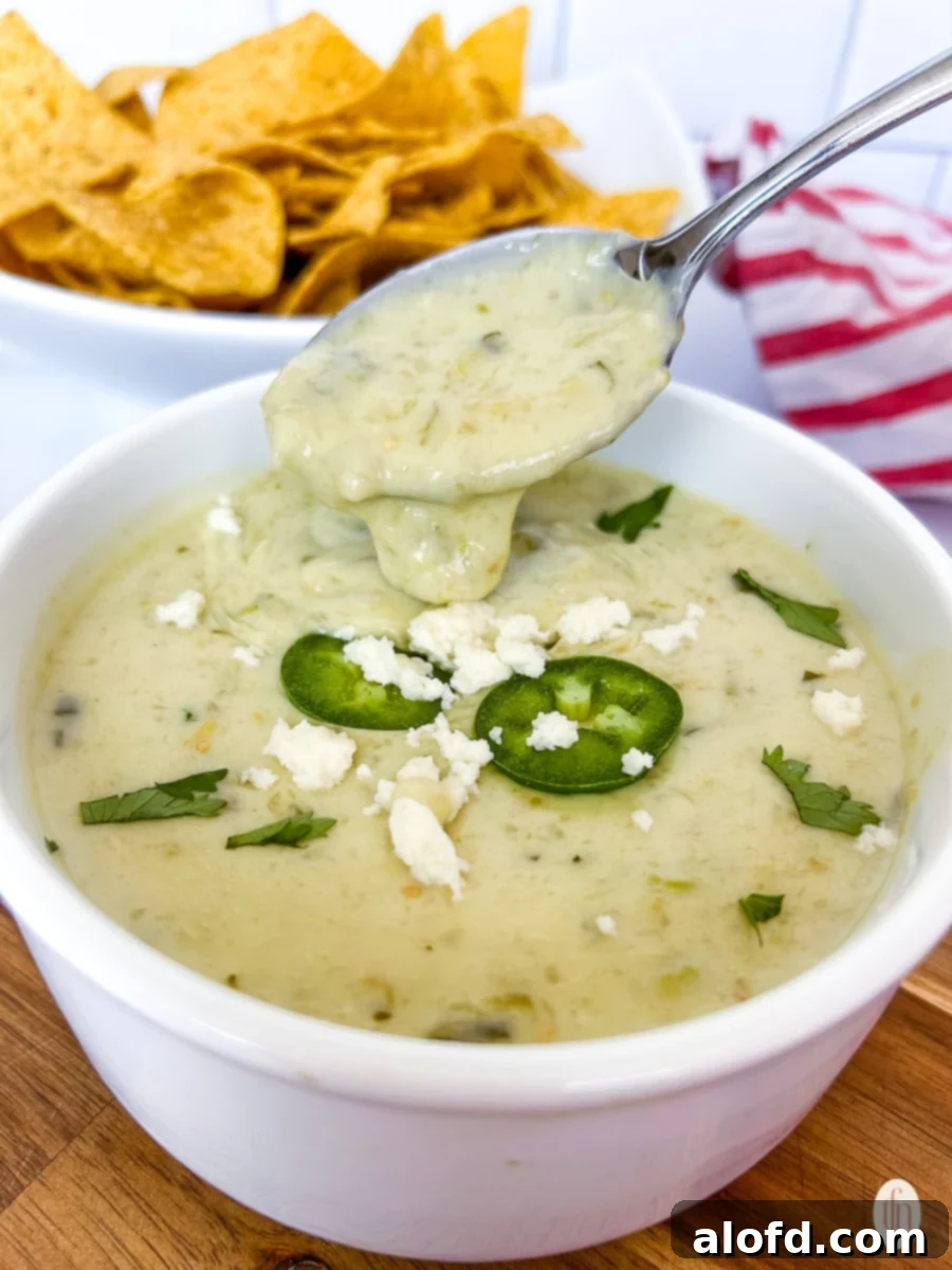 Spoon holding soup above a bowl.