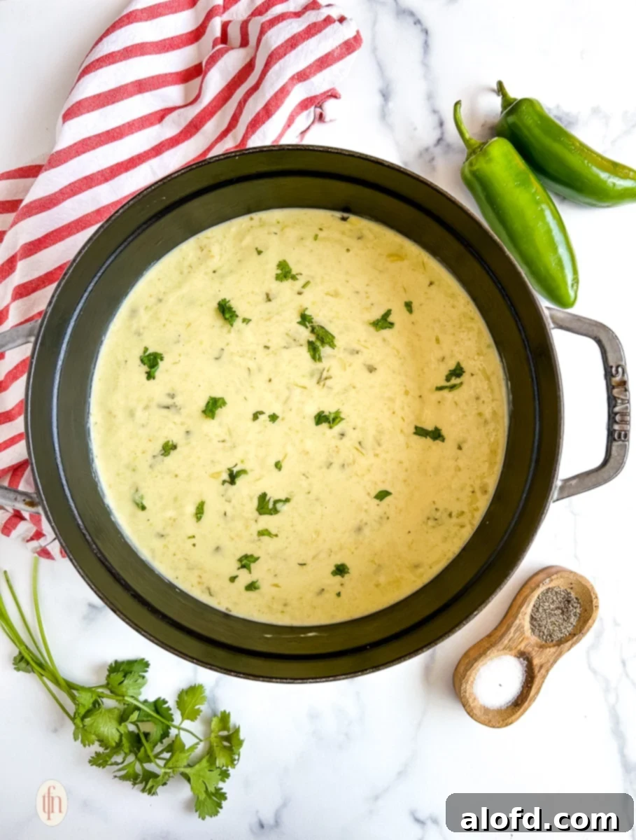 Overhead image of cream of jalapeno soup in a pot on a white surface.