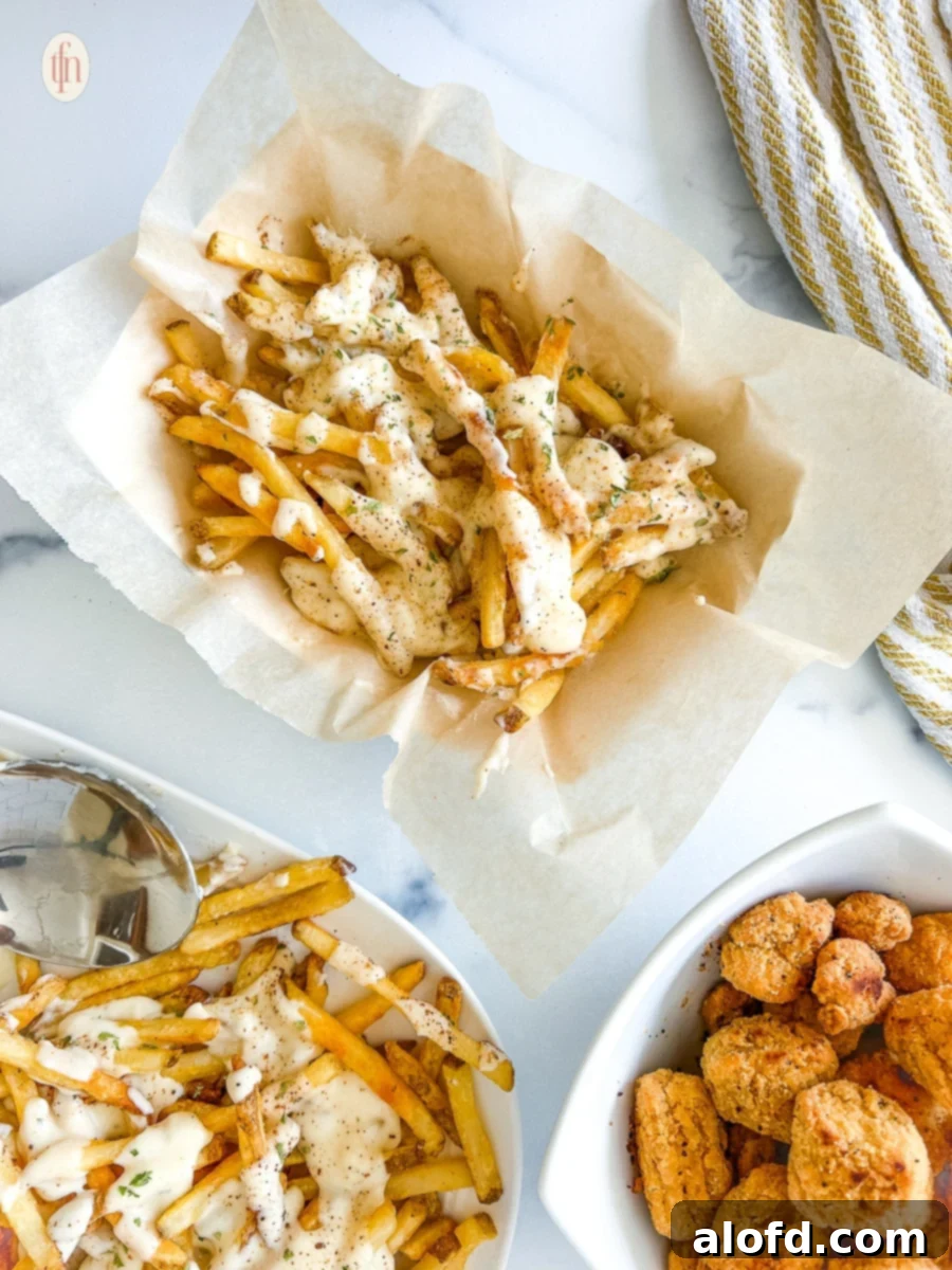 Voodoo Kitchen Fries 3 Two plates filled with French fries generously covered in a white, creamy sauce, ready to be served.