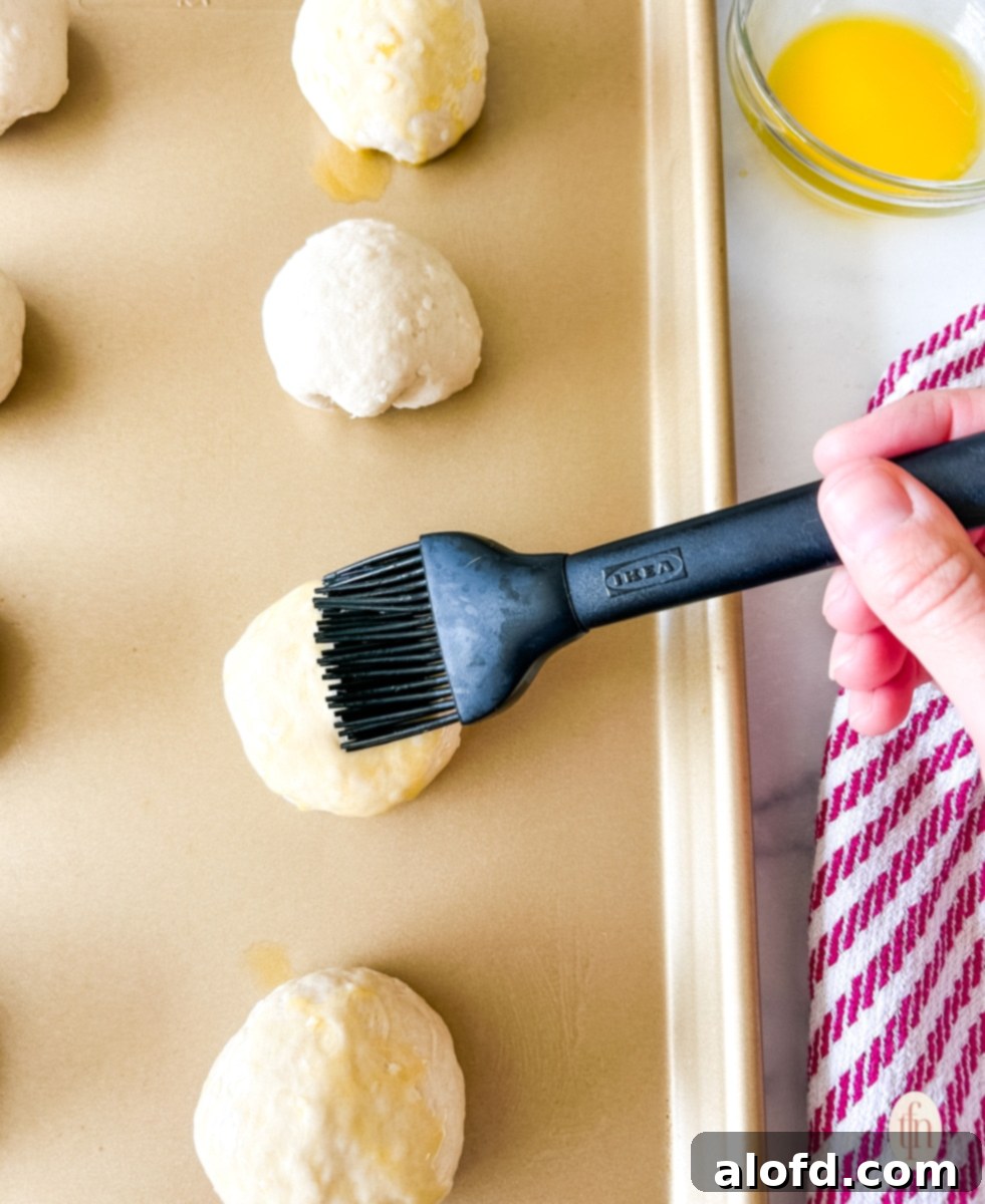 Fiery Buffalo Chicken Poppers 9 A basting brush applying melted butter to the tops of buffalo chicken bombs arranged on a baking tray, ready for or just out of the oven.