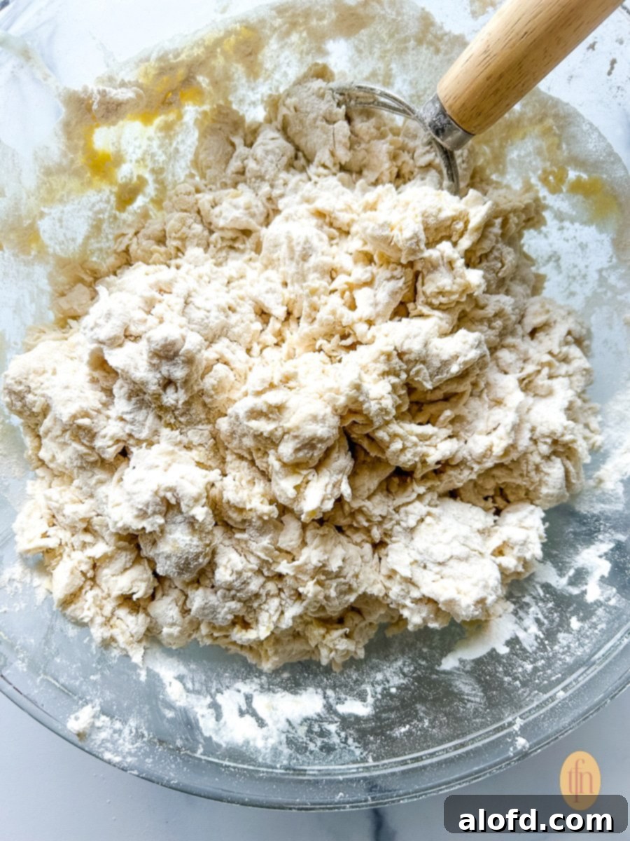 Shaggy looking mixture of water and flour combined together with a whisk in a mixing bowl.