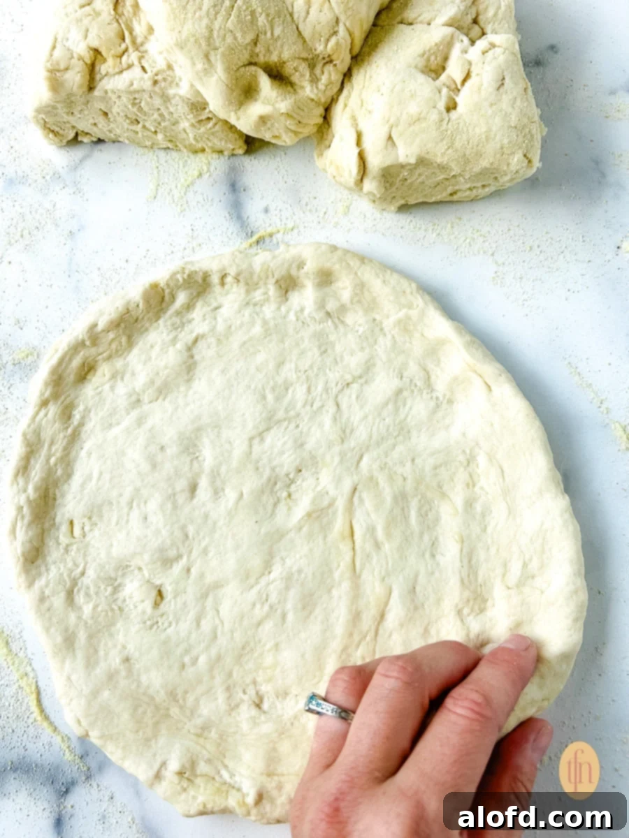 Woman's hand shaping pizza dough sourdough discard.