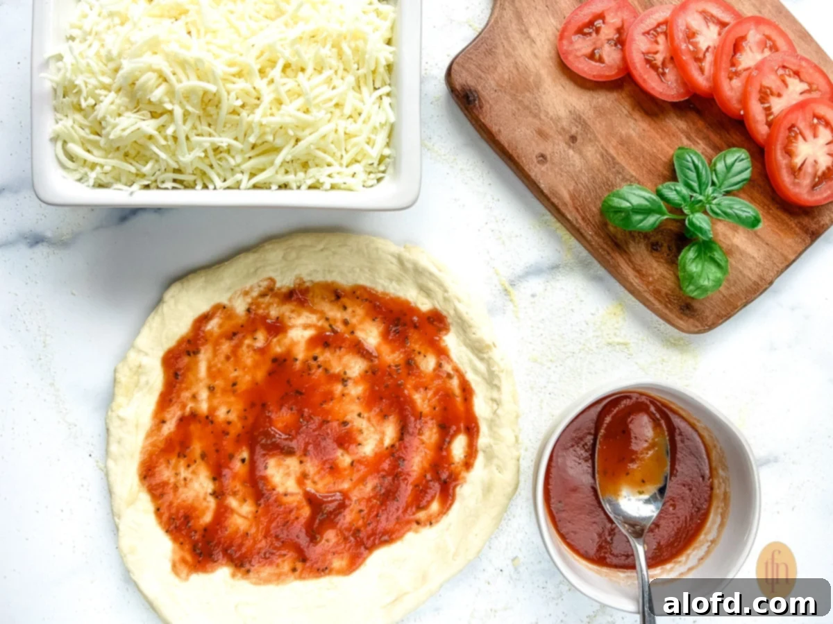 Assembling sourdough discard pizza crust with toppings and cheese.