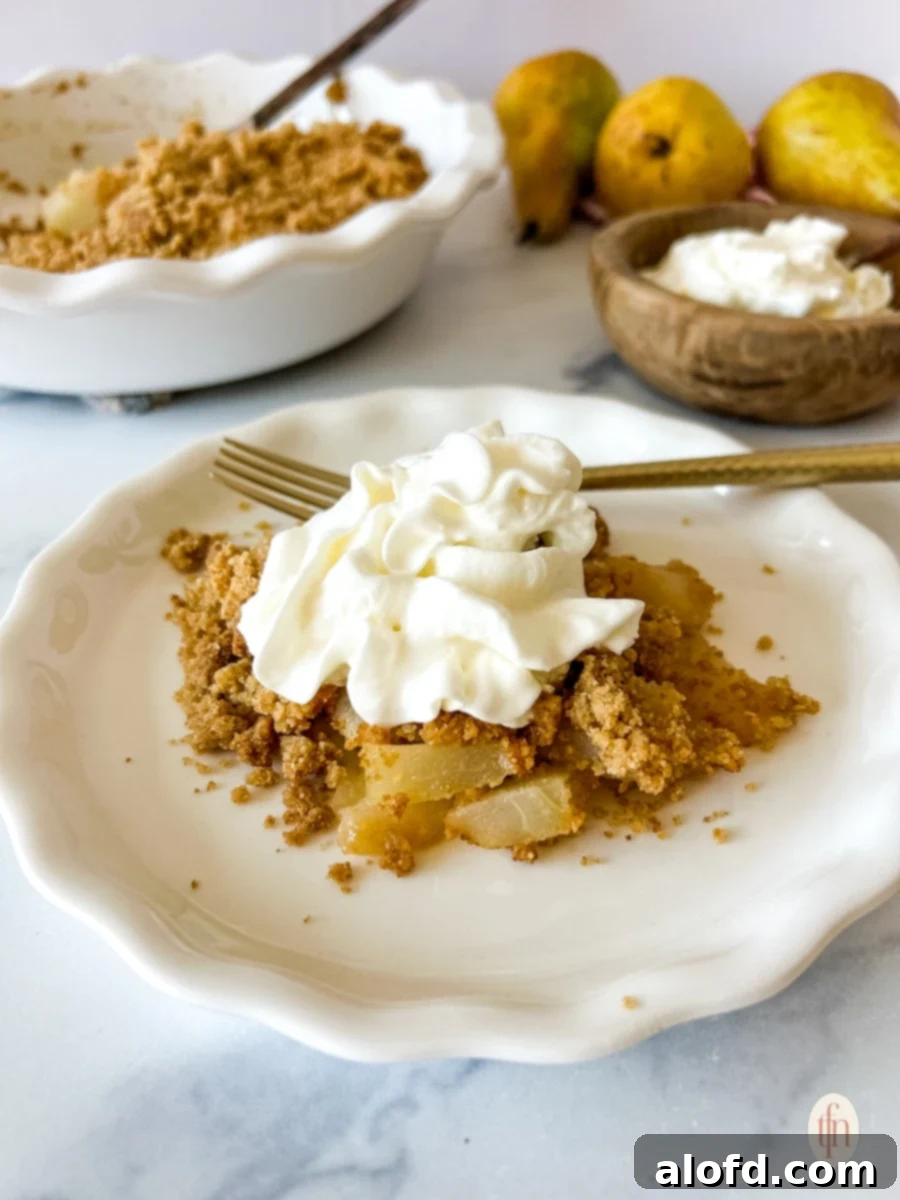White plate with pear crumble and whipped cream on top.