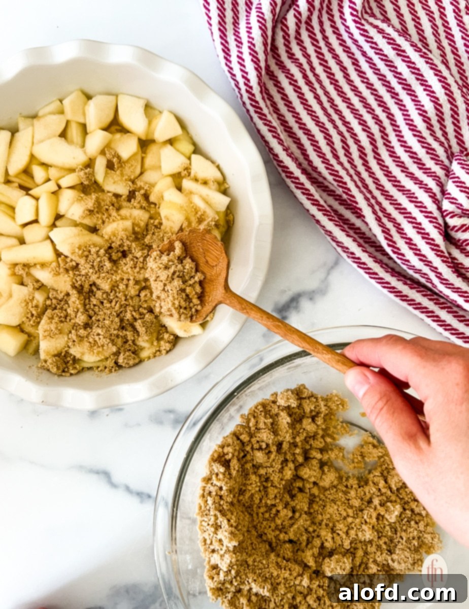Topping pears with the crumble in a white baking dish.