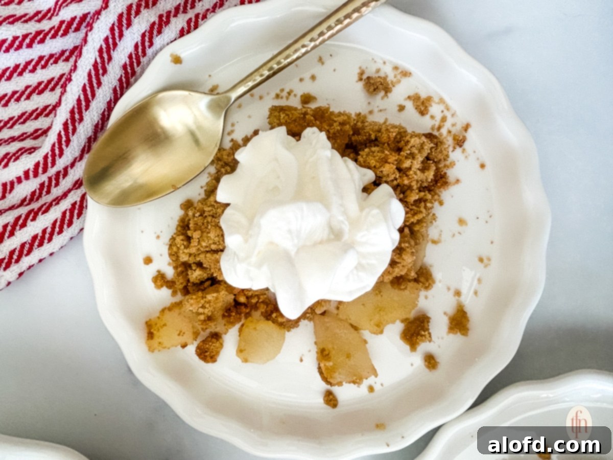 Pears and whipped cream on a white plate with a spoon on top.