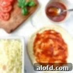 Sourdough Discard Demystified 13 Sauce, cheese, fresh tomato slices and shredded mozzarella cheese surround a crust with red sauce on it.