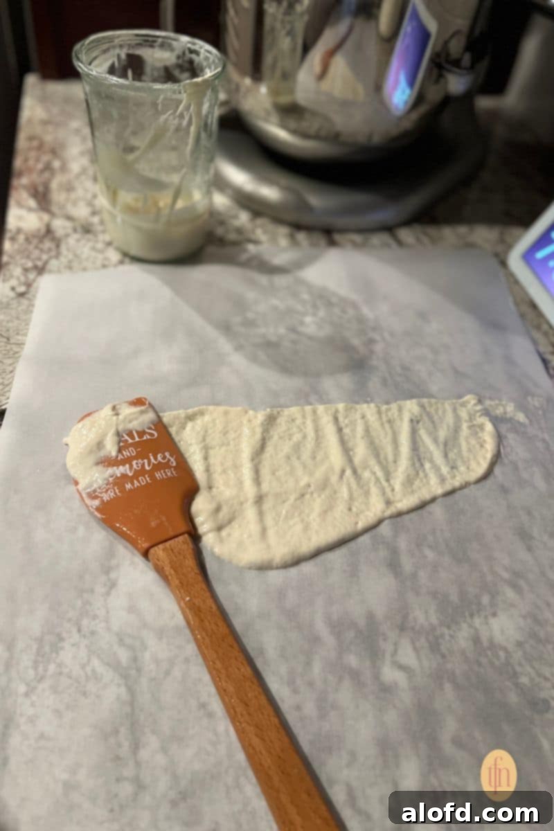 Sourdough Discard Demystified 8 Sourdough starter spread on a parchment paper using a rubber scrapper.