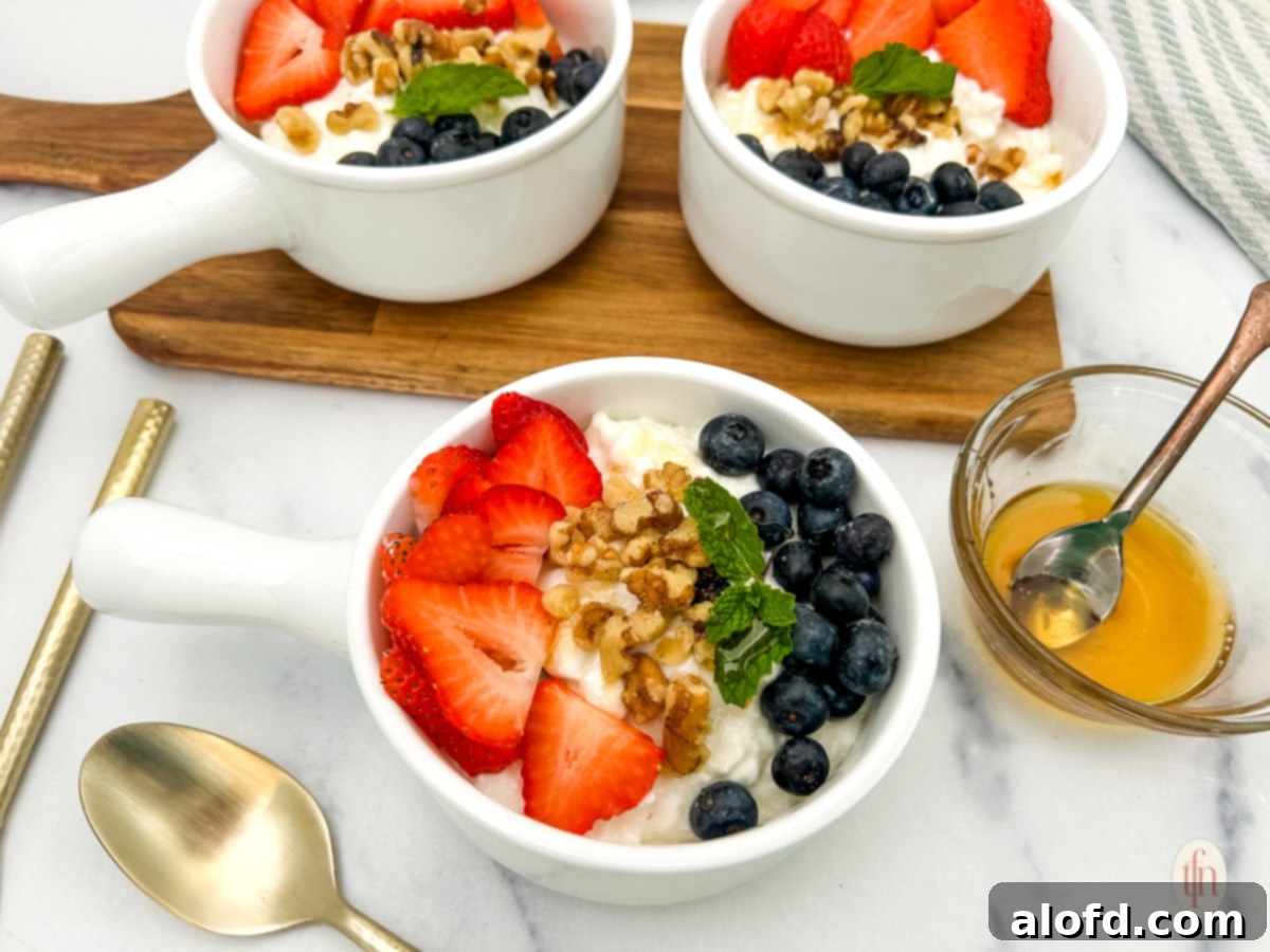 Nourishing Cottage Cheese Creation 11 Three cottage cheese and fruit bowl with a bowl of honey with spoon.