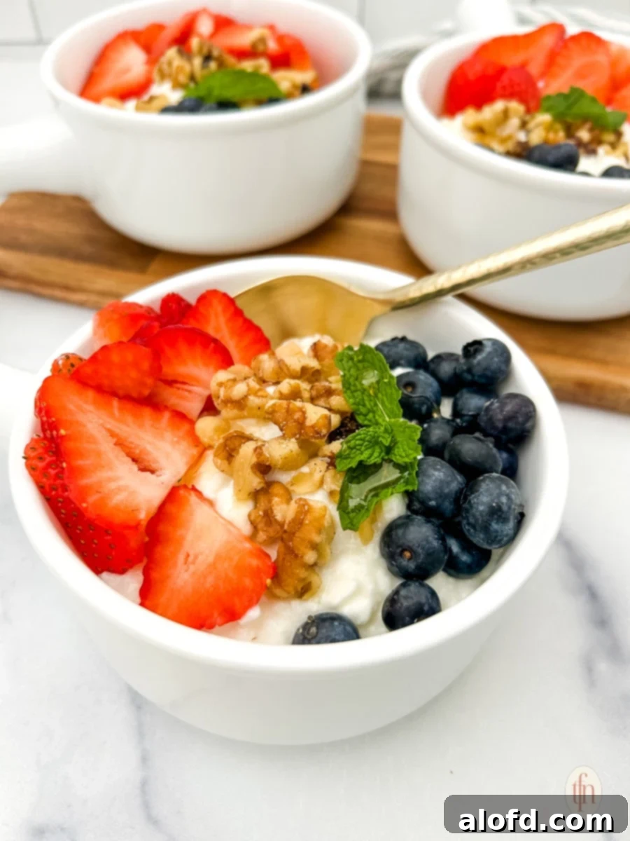 Nourishing Cottage Cheese Creation 10 Cottage cheese and fruit bowl with spoon and two more served bowls at the back.
