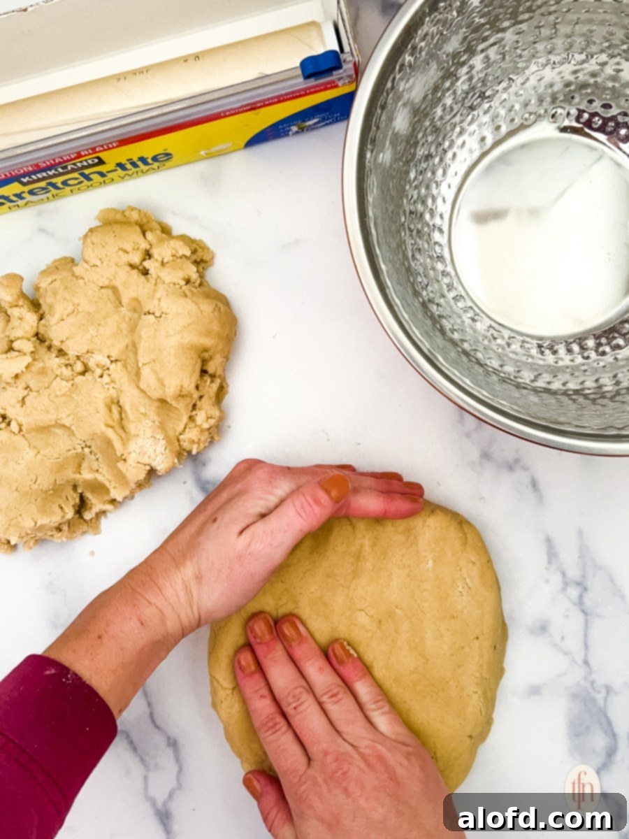 Sweetheart Delights 7 Raw cookie dough being formed into a ball and wrapped in cling wrap, ready for refrigeration.