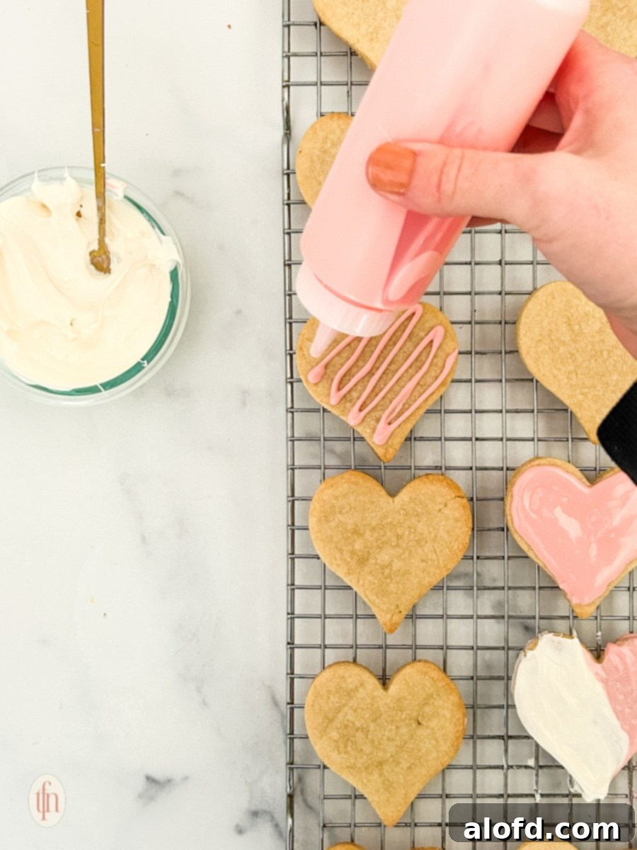 Sweetheart Delights 9 Heart cookies being decorated with frosting on a cooling rack, showcasing the final step.