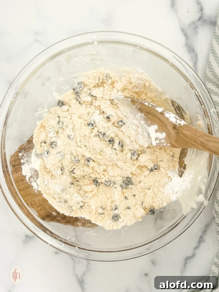 Artisan Sourdough Blueberry Scones 6 Mixed ingredients for blueberry sourdough scones in a bowl with a wooden ladle.