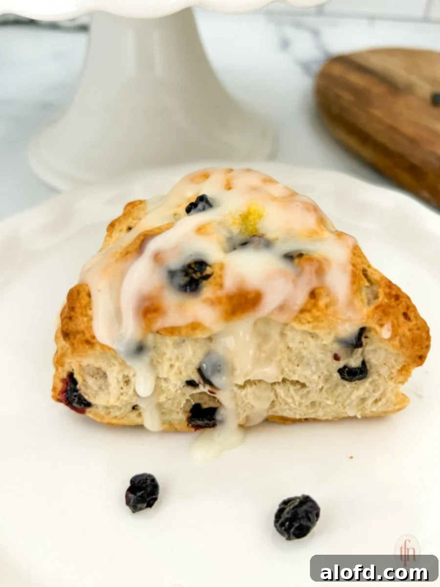 Artisan Sourdough Blueberry Scones 9 A platter of blueberry sourdough scones, some with lemon glaze, on a white plate.